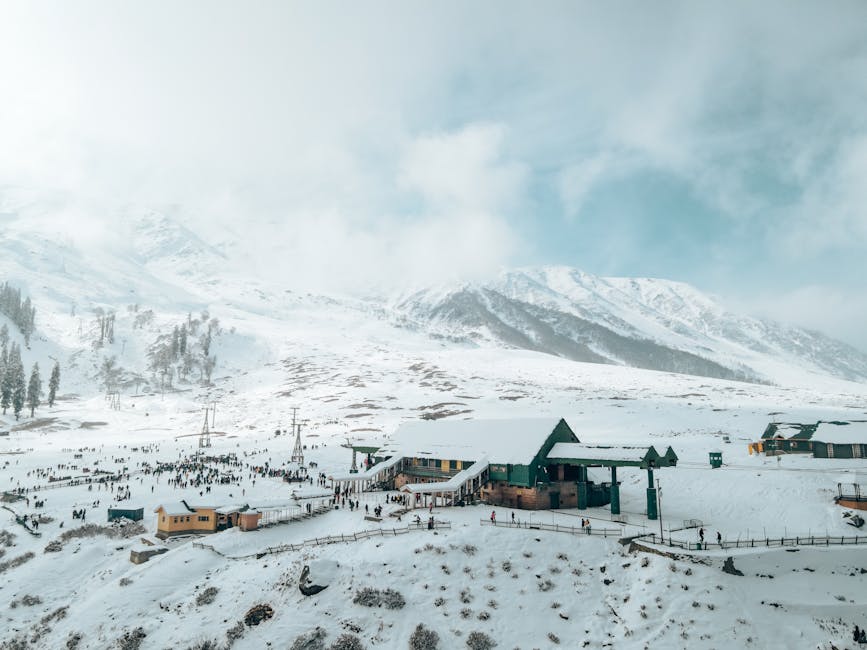 Stunning aerial view of snow-covered Gulmarg landscape with ski resort and distant mountains.
