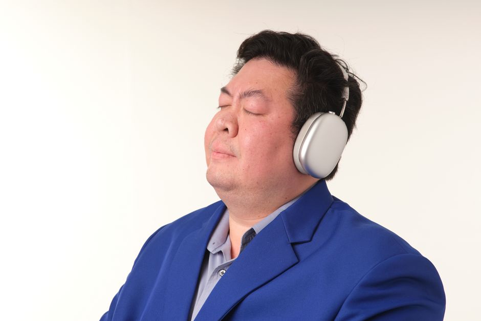 Adult man in a blue suit enjoying music with headphones. Calm and relaxed expression.