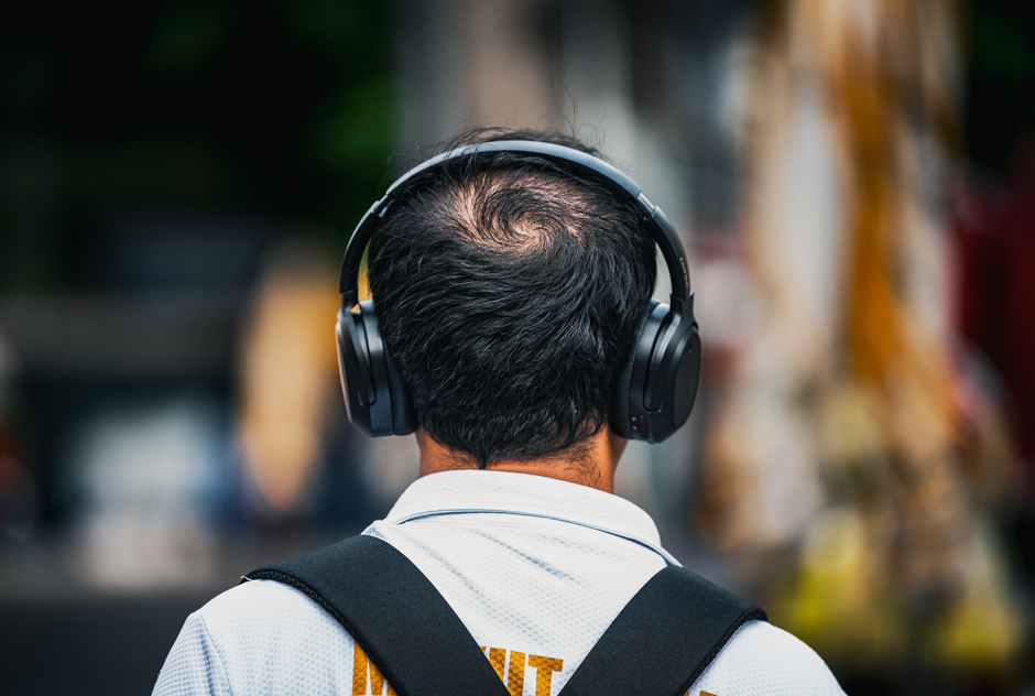 Rear view of a man wearing headphones in Bangkok, Thailand. Urban street scene.