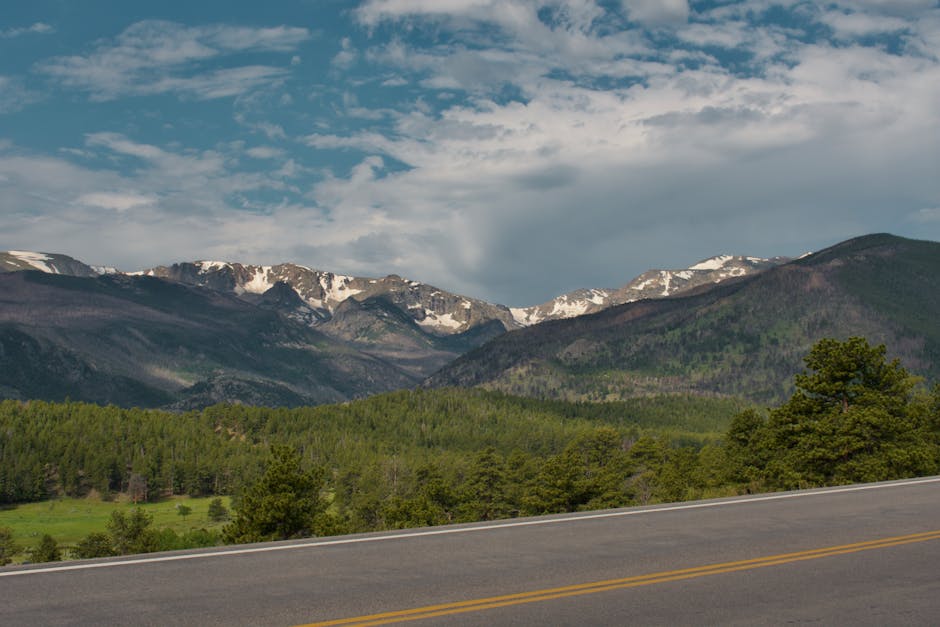 Breathtaking view of snow-capped mountains and green forest in Rocky Mountain National Park.