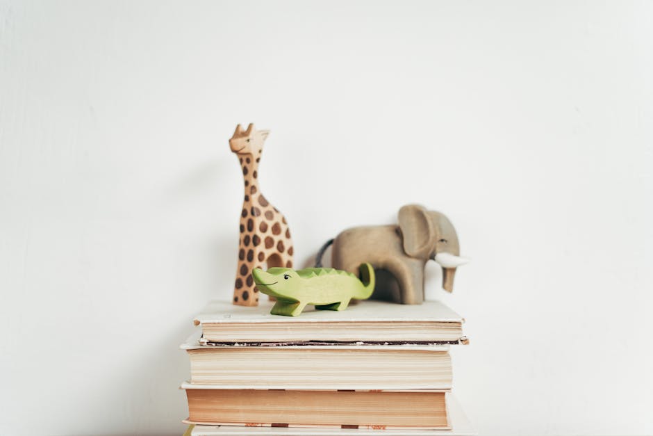 Stack of books with wooden toy giraffe, elephant, and crocodile on a white background. Ideal for educational themes.