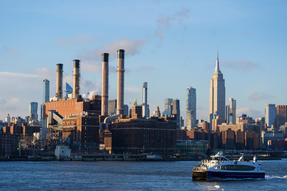 Scenic New York City skyline view with iconic architecture and ferry crossing the river.