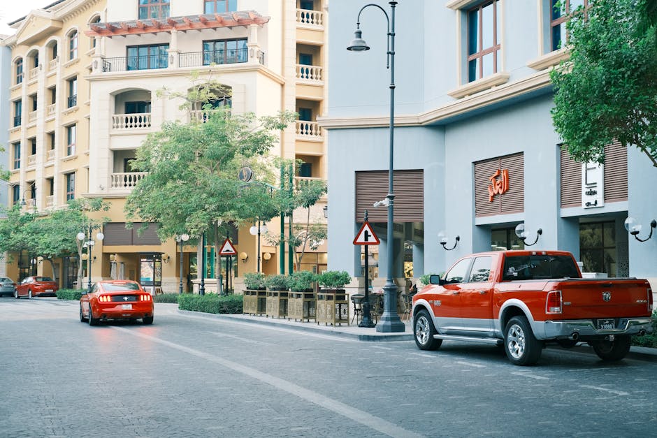 A vibrant urban street scene featuring red cars and classic architecture on a sunny day.